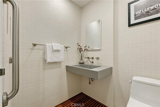 bathroom with sink, tile walls, and toilet