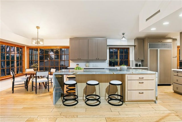 kitchen with a kitchen island, light hardwood / wood-style floors, paneled built in fridge, and a notable chandelier