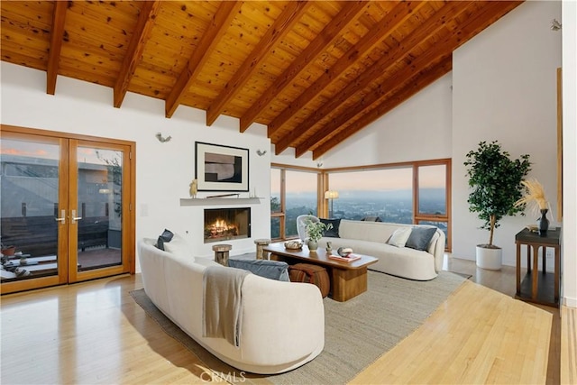 living room with wooden ceiling, light wood-type flooring, french doors, high vaulted ceiling, and beam ceiling