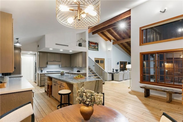 kitchen featuring a notable chandelier, beamed ceiling, light hardwood / wood-style floors, and a center island