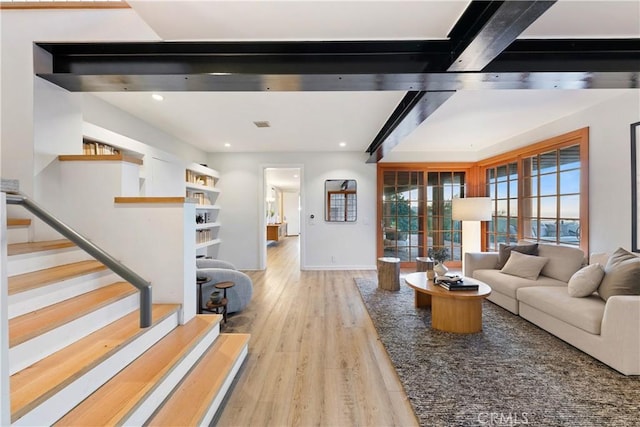 living room featuring beamed ceiling and light hardwood / wood-style flooring