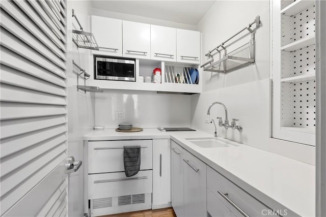 kitchen featuring stainless steel microwave, white cabinets, and sink