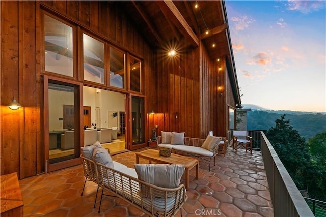 patio terrace at dusk featuring a balcony and an outdoor living space