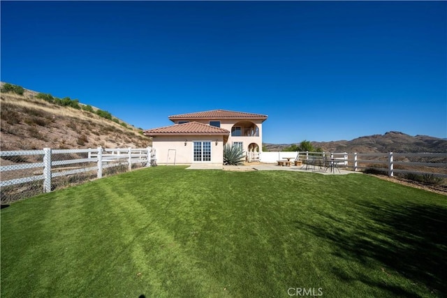 back of house with a lawn, a patio area, and a mountain view