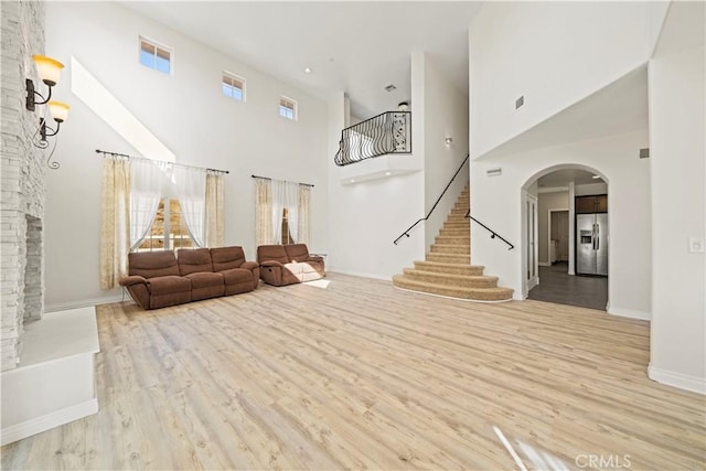 unfurnished living room featuring light wood-type flooring, a fireplace, and a high ceiling