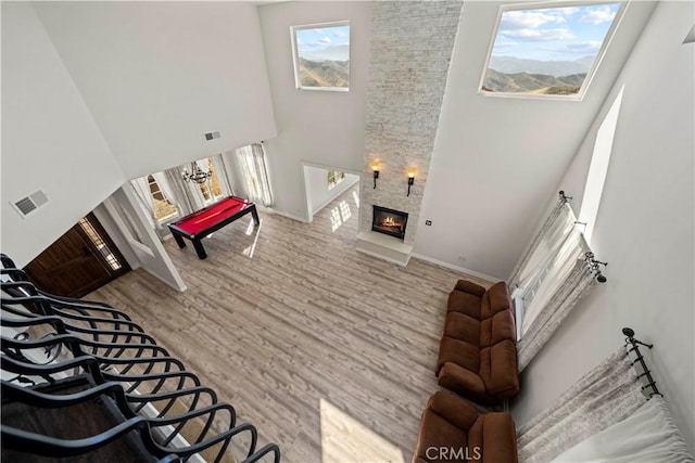 living room featuring wood-type flooring, a towering ceiling, and a stone fireplace