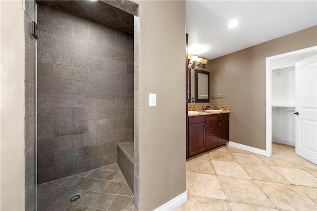 bathroom featuring tiled shower, vanity, and tile patterned flooring