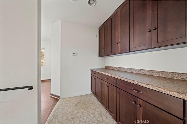 kitchen with dark brown cabinetry and light wood-type flooring