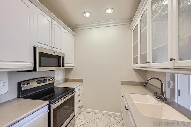 kitchen with stainless steel appliances, ornamental molding, white cabinetry, and sink