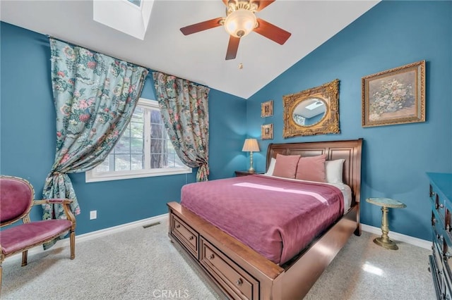 bedroom featuring ceiling fan, vaulted ceiling with skylight, and light carpet