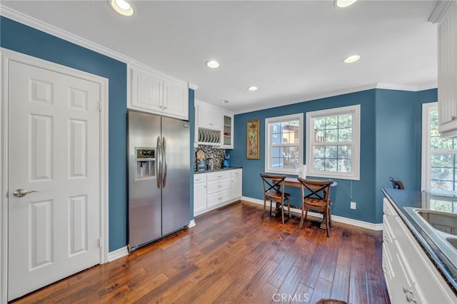 kitchen with white cabinets, dark wood-type flooring, backsplash, stainless steel fridge, and ornamental molding