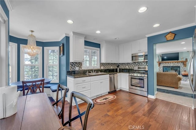 kitchen with pendant lighting, sink, white cabinetry, appliances with stainless steel finishes, and dark hardwood / wood-style flooring