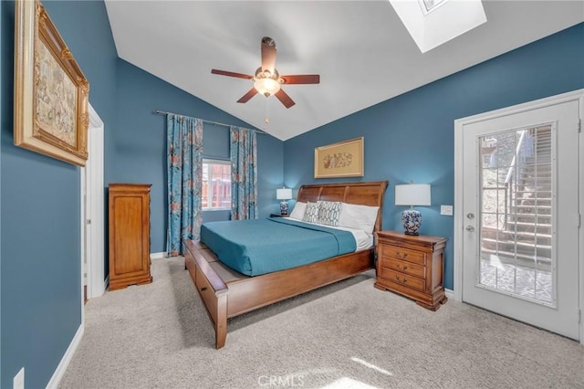 carpeted bedroom with ceiling fan, vaulted ceiling with skylight, access to outside, and multiple windows