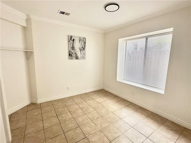 empty room with light tile patterned flooring and ornamental molding