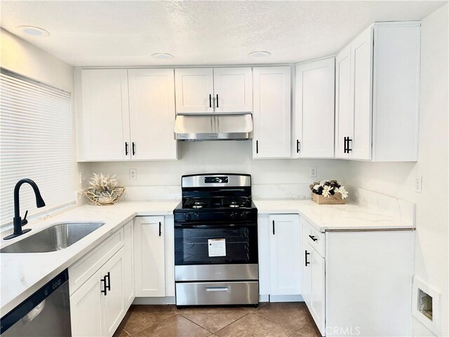 kitchen with appliances with stainless steel finishes, tile patterned floors, white cabinetry, and sink