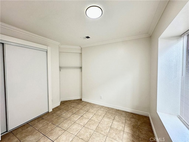 unfurnished bedroom with light tile patterned floors, a closet, and ornamental molding