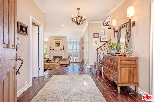 foyer with dark wood-type flooring, a chandelier, crown molding, and french doors