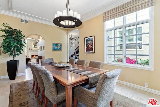 dining area featuring crown molding, a healthy amount of sunlight, and an inviting chandelier