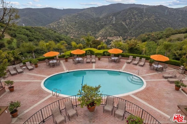 view of swimming pool with a patio area and a mountain view