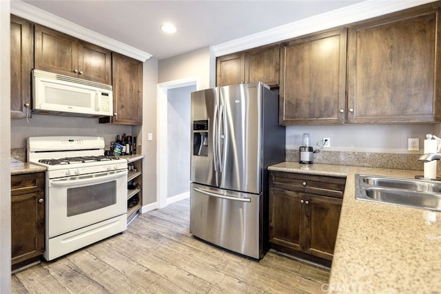 kitchen featuring white appliances, dark brown cabinetry, sink, ornamental molding, and light wood-type flooring