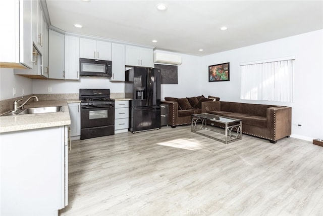 kitchen with black appliances, sink, white cabinetry, light hardwood / wood-style flooring, and a wall mounted air conditioner