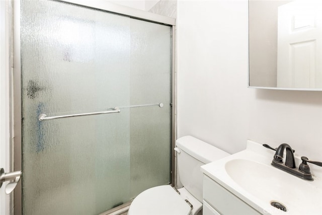 bathroom featuring toilet, vanity, and a shower with door