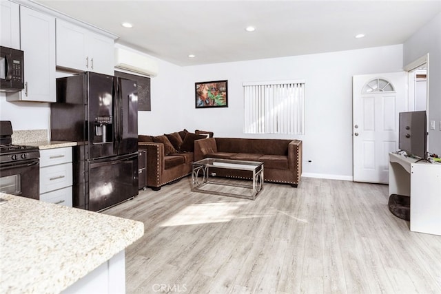 kitchen featuring light stone countertops, light hardwood / wood-style flooring, white cabinets, and black appliances