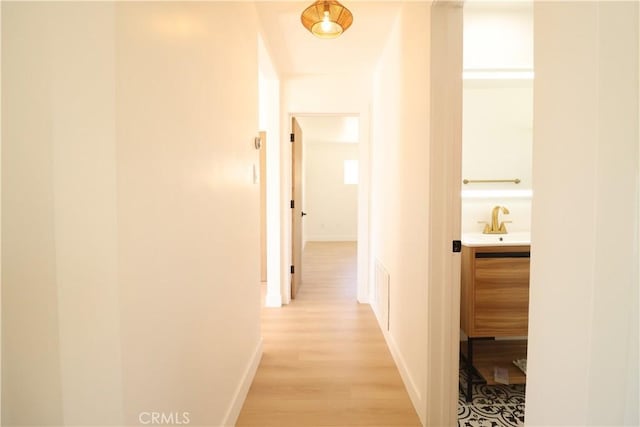 hallway with sink and light hardwood / wood-style flooring