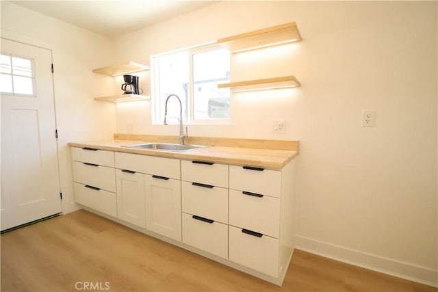 kitchen featuring sink, white cabinetry, and light wood-type flooring