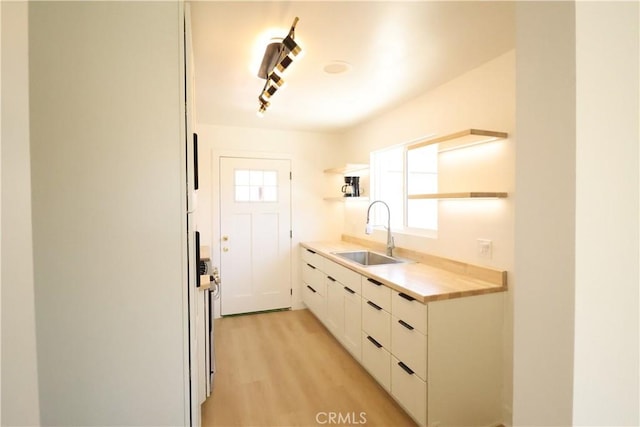 kitchen featuring light wood-type flooring, white cabinetry, and sink