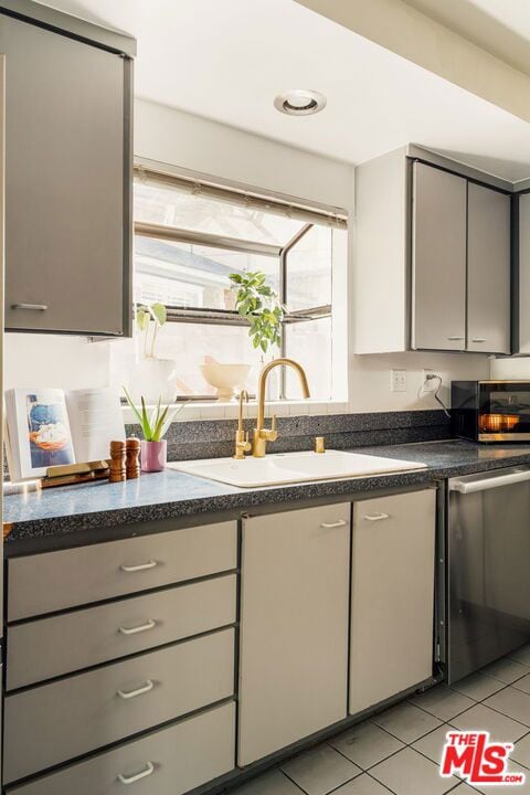 kitchen featuring gray cabinetry, sink, light tile patterned flooring, and stainless steel appliances