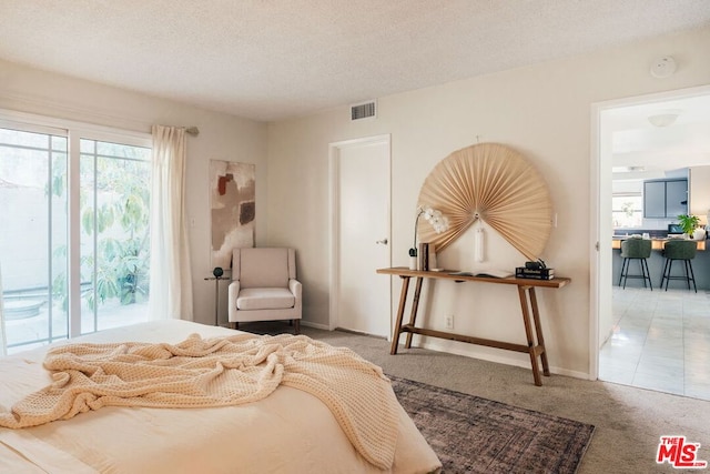 carpeted bedroom featuring a textured ceiling and access to outside