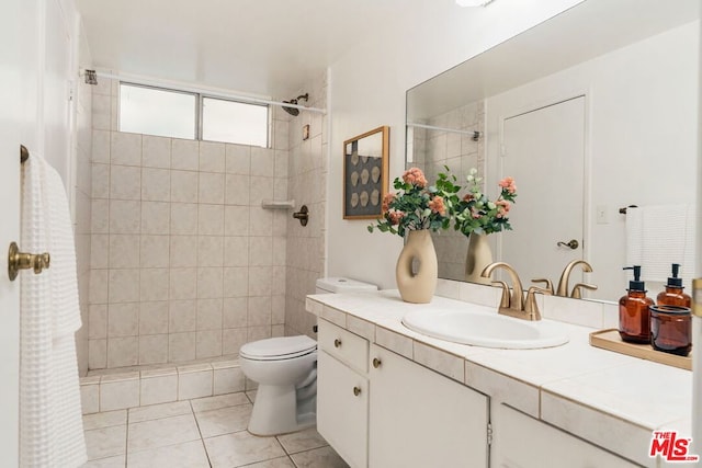 bathroom with tile patterned flooring, vanity, toilet, and a tile shower