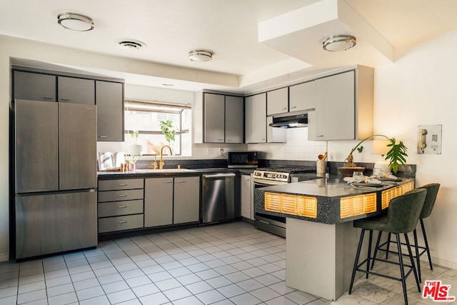 kitchen with gray cabinetry, kitchen peninsula, sink, and appliances with stainless steel finishes