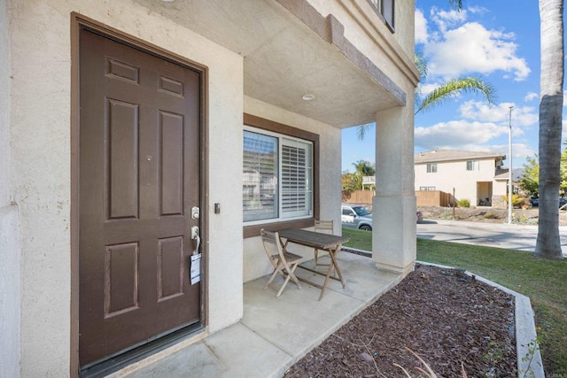 doorway to property featuring covered porch and stucco siding