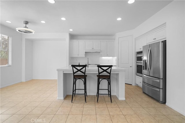 kitchen featuring a kitchen bar, light tile patterned floors, white cabinets, and stainless steel appliances