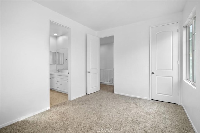 unfurnished bedroom with ensuite bath, light colored carpet, and sink