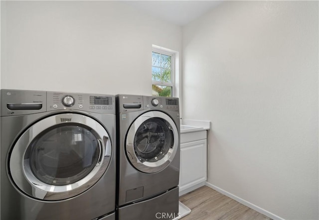 washroom with cabinets, separate washer and dryer, and light hardwood / wood-style floors