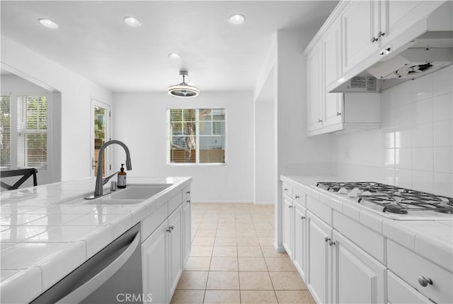 kitchen with tile counters, white cabinets, sink, and light tile patterned floors