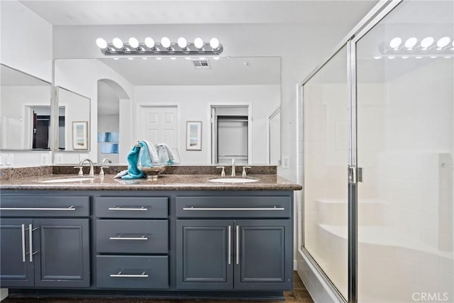 bathroom with visible vents, a sink, a shower stall, and double vanity