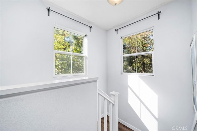 hall featuring a wealth of natural light, baseboards, and an upstairs landing