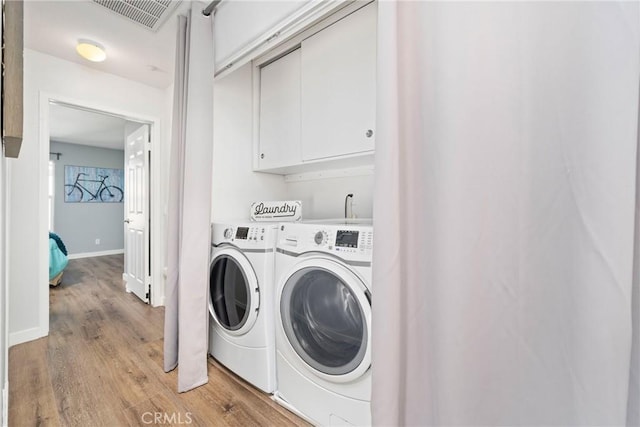 washroom with light wood-style floors, washing machine and dryer, visible vents, and baseboards