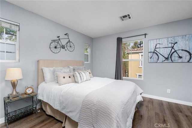 bedroom with dark wood-style floors, visible vents, and baseboards