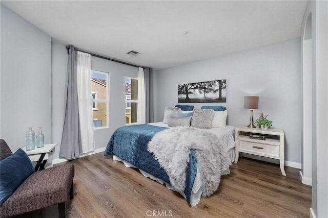 bedroom with wood finished floors, visible vents, and baseboards