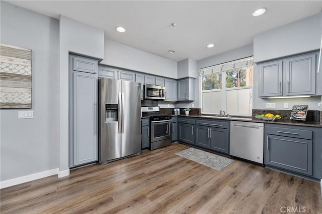 kitchen with dark countertops, stainless steel appliances, dark wood finished floors, and gray cabinetry