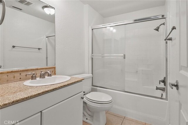 full bathroom featuring bath / shower combo with glass door, toilet, vanity, and tile patterned flooring