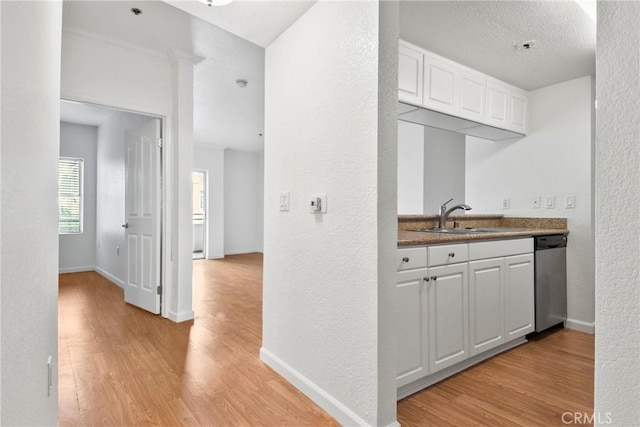 kitchen with white cabinetry, light hardwood / wood-style floors, dishwasher, and sink