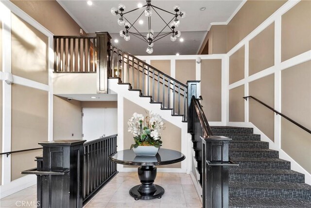 stairway with a chandelier, a towering ceiling, and ornamental molding