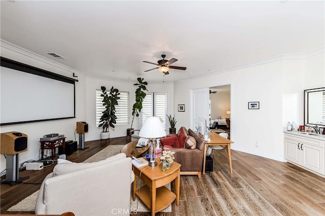 cinema featuring ceiling fan, sink, ornamental molding, and light hardwood / wood-style flooring