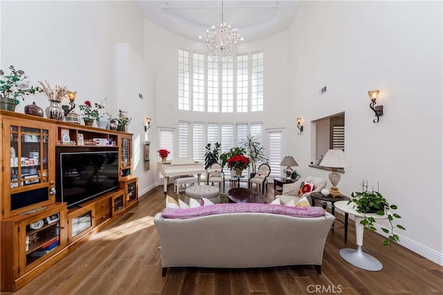 living room with a high ceiling, wood-type flooring, and a notable chandelier